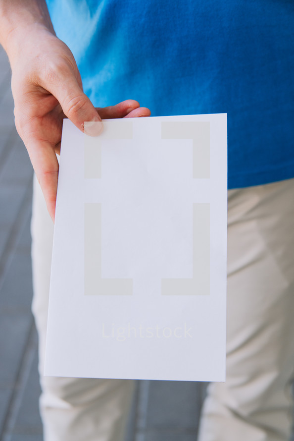 Close up of a man holding out a blank flyer.