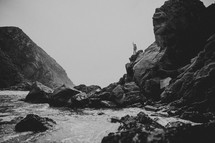 woman standing on top of rocks near the ocean
