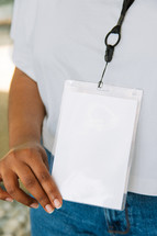 Woman in a white tshirt wearing a large lanyard.