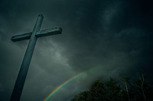a cross in a gray sky and a rainbow 