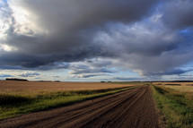 long and empty gravel road under moody evening skies