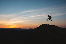 silhouette of a leaping man at sunset on a mountaintop 