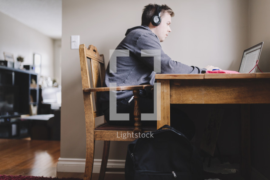 a young man reading on his laptop with headphones on