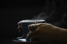 a woman holding a steaming cup of coffee 