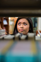 woman looking over books on a bookshelf in a library