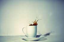 Coffee splashes out of a white coffee mug