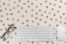 computer keyboard and mouse and  reading glasses on a polka dot background 
