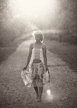 barefoot woman walking on a dirt road