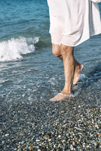 a woman standing with her feet in the ocean 