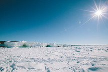 Snow covered land and ice hills, with bright sun in a blue sky