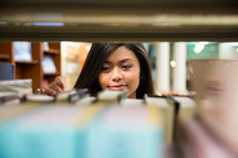 woman looking at books on a bookshelf in a library 