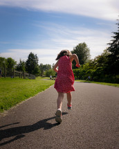 little girl running on a paved path 