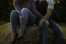 a couple sitting on a hay bale 