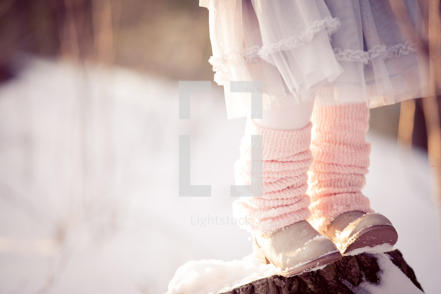 a girl with leg warmers standing in the snow 