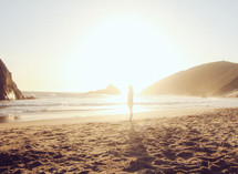 silhouette of a woman standing on a beach at sunrise 