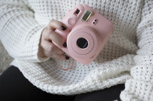 a woman holding a pink camera