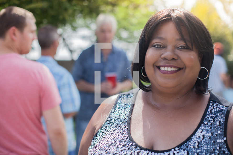 headshot of a woman and friends standing around talking at a backyard summer party