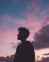 A young man looking with head looking up towards the sky at sunset