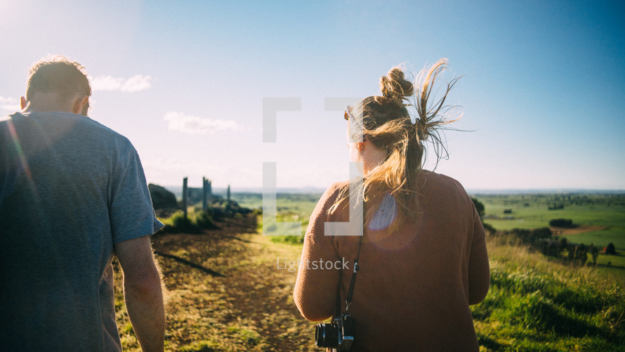 man and woman walking towards a beach with a camera 