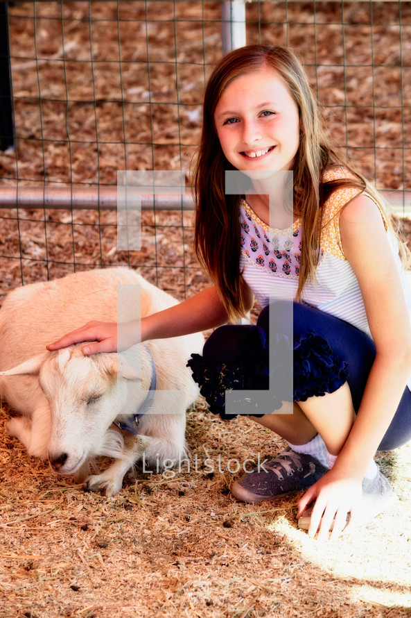 a child petting a goat at a petting zoo 