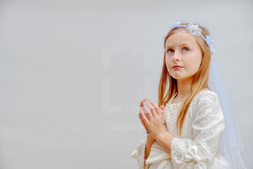 First Communion portrait of a little girl in a white dress with rosary beads 