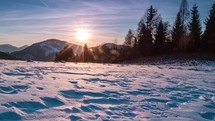 Beautiful nature sunset over forest and snowy meadow in cold winter evening Time lapse