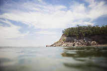 A cliff packed with trees on the horizon flanked by the ocean.