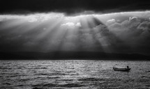 rays of sunlight over an empty boat floating on water 