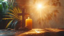 Wooden cross, candle and palm leaves on wooden table in sunlight.