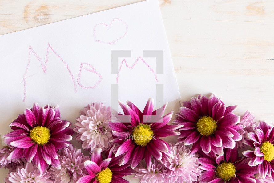 Word mom written on white card with pink daisies