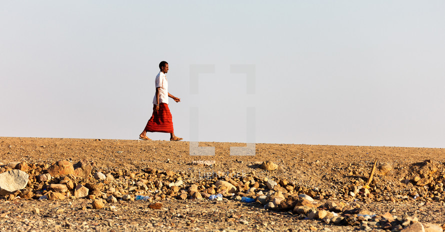 man walking across a desert in Ethiopia 