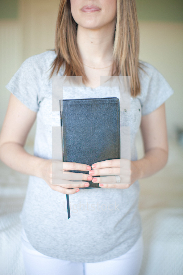 Smiling woman holding closed Bible.