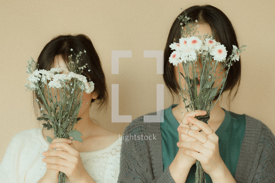 girls holding bouquets of daisies 