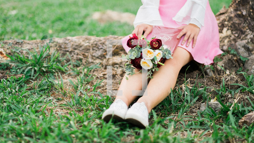 a woman sitting in the grass with a bouquet of flowers in her lap 