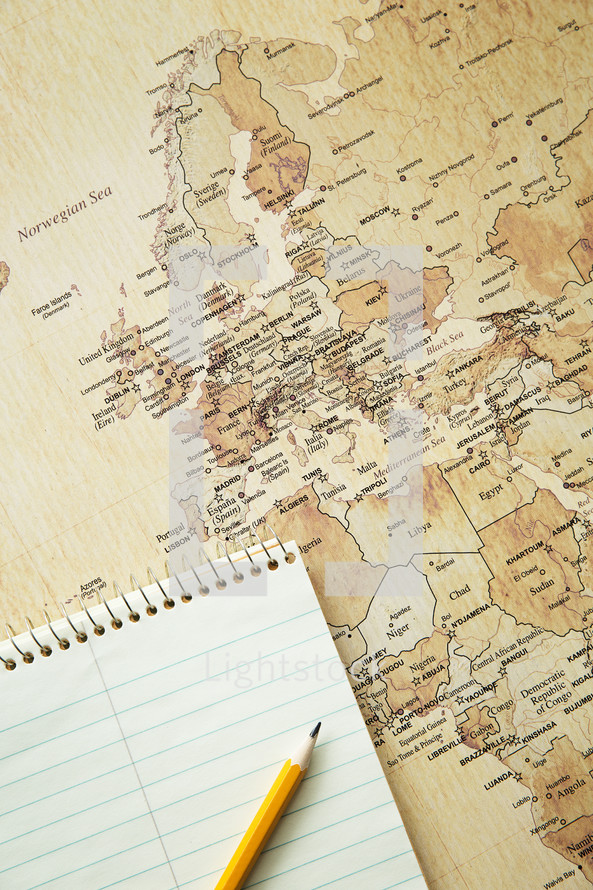 notebook and pencil on a world map 