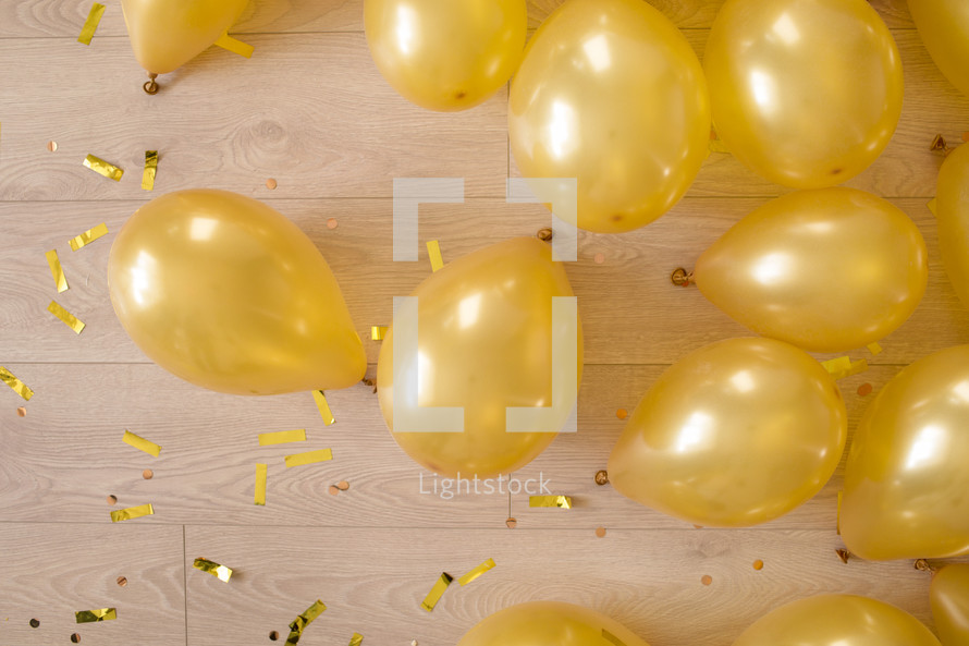 golden balloons and confetti on a wooden floor. preparation for a birthday or other party