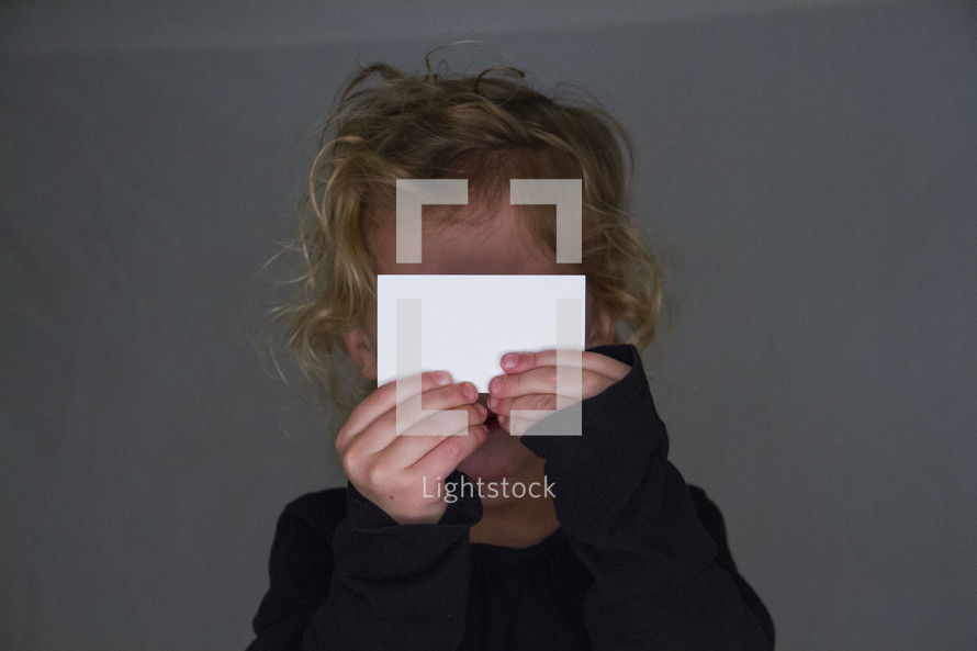a child holding up a blank notecard 