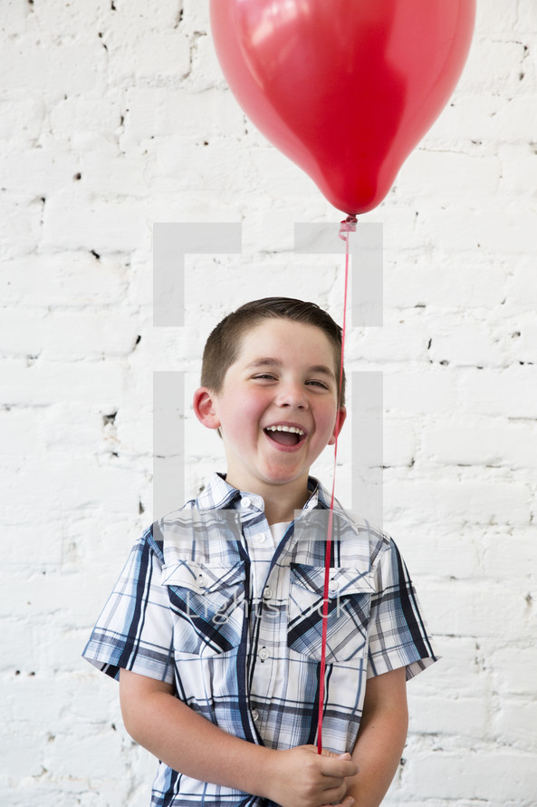 a boy child holding a red balloon 