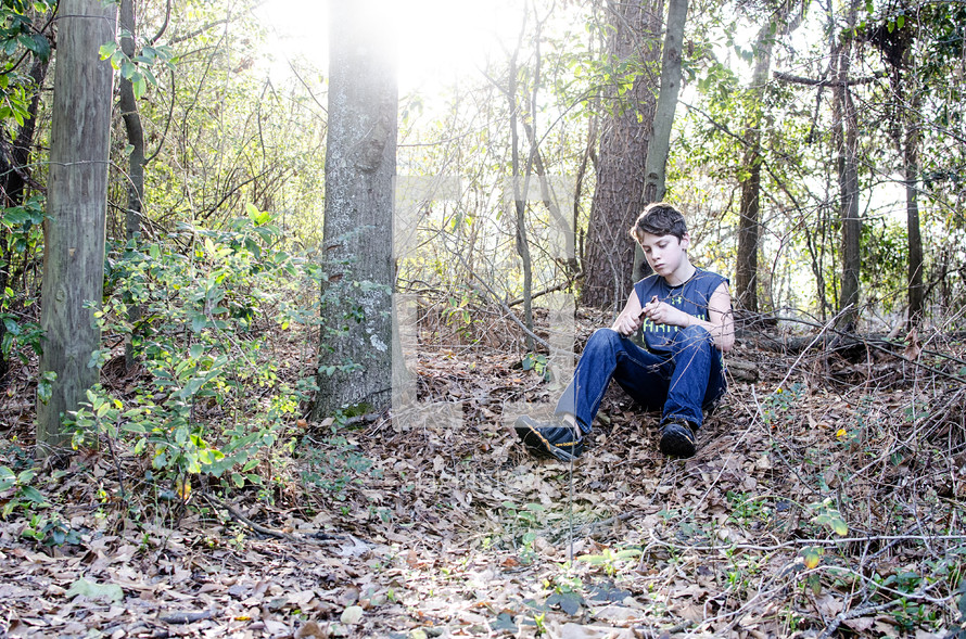 a boy sitting in a forest 
