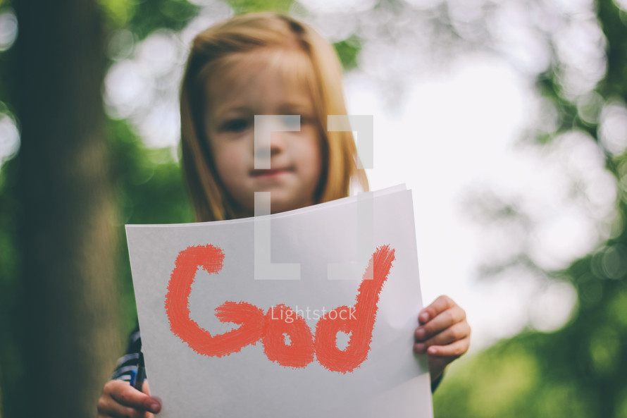 A child holding a handwritten sign saying, "God."