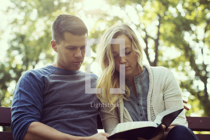 a couple reading a Bible together outdoor 