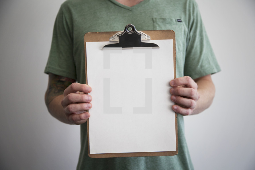 man holding a blank piece of paper on a clipboard 