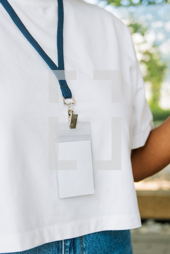 Woman in a white tshirt wearing a lanyard.