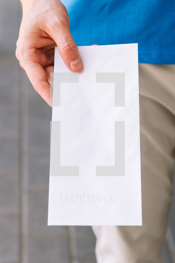 Close up of a man holding out a blank flyer.