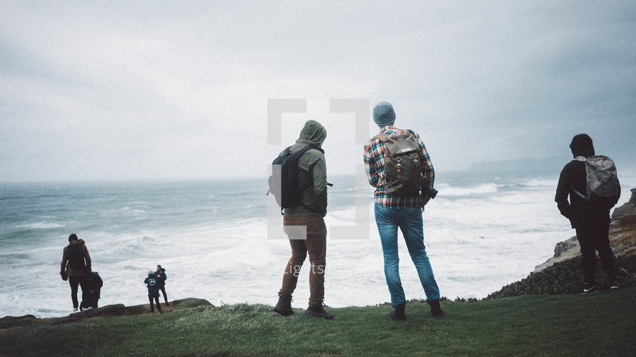 men standing along the edge of cliffs along a shore 
