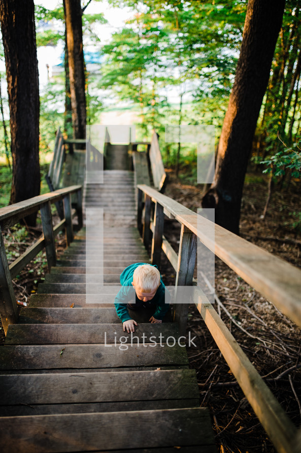 toddler boy on steps outdoors by a lake 