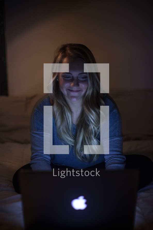 young woman looking at her computer screen in a dark room 