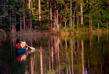 two young boys canoeing in a pond to go fishing
