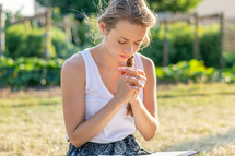 a woman reading a Bible outdoors and praying 