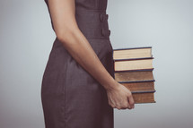 a woman holding a stack of books 